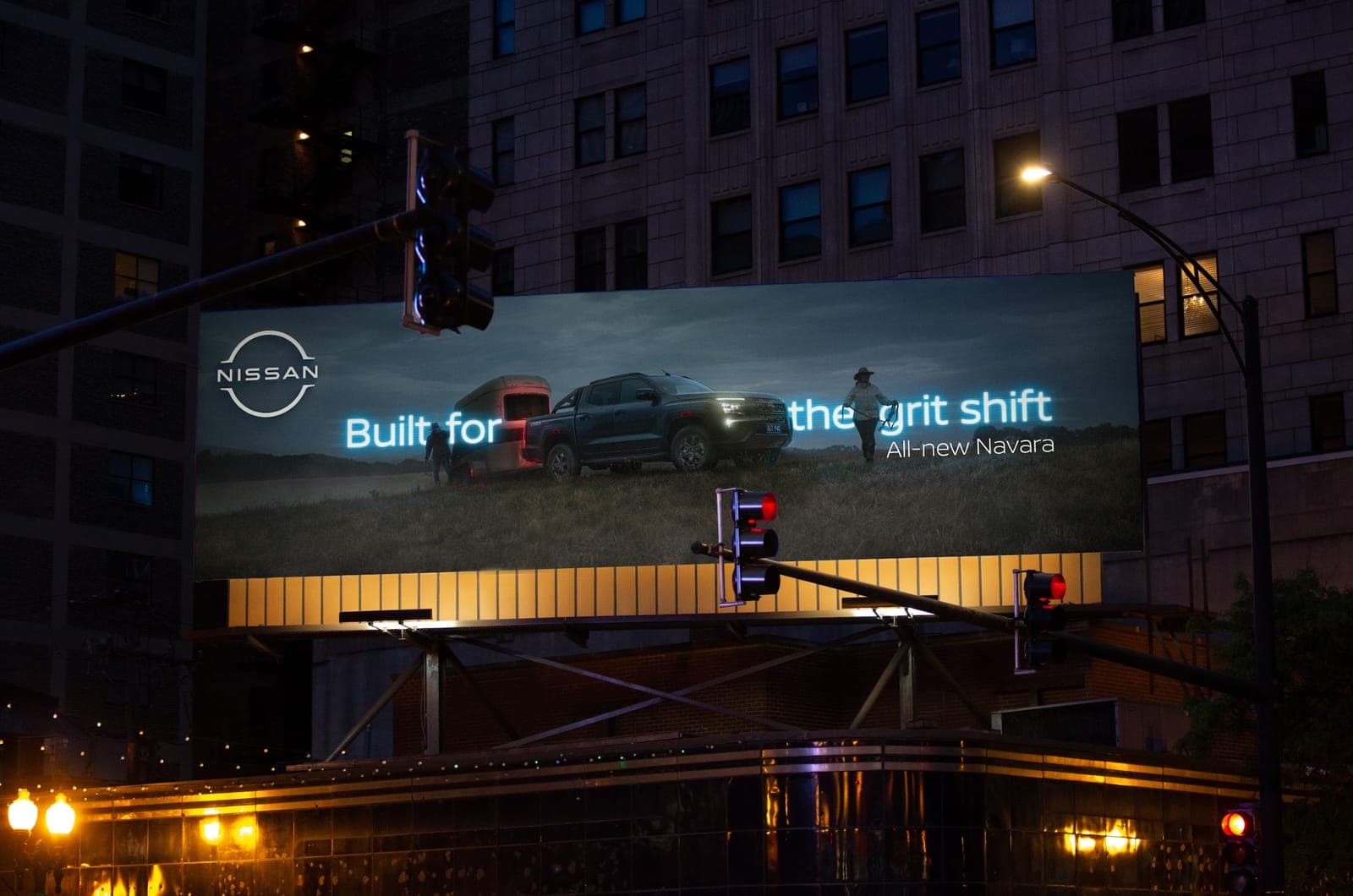 Built for the grit shift billboard lit up above a city intersection at night, showing a Navara towing a horse float across a dark paddock